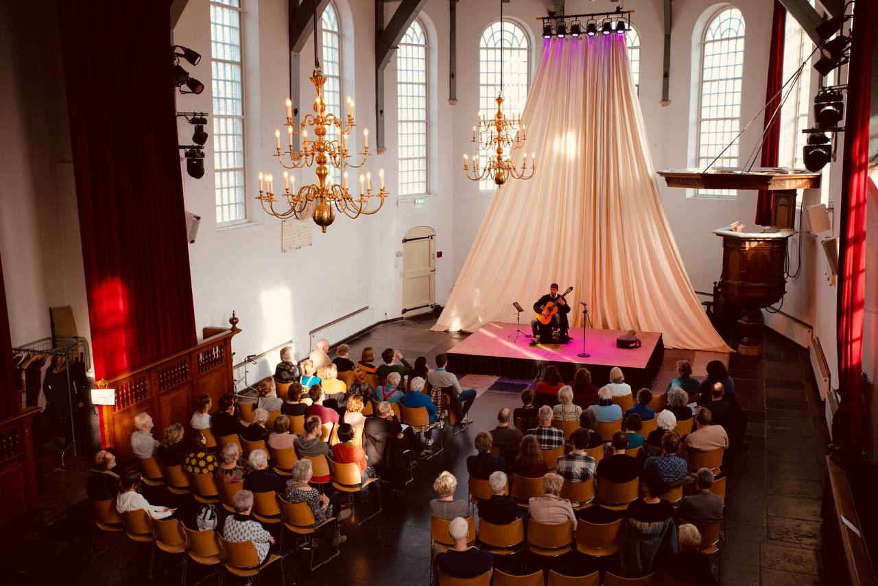 Silvan de Smit speelt klassieke gitaar voor publiek in de Buiksloterkerk in Amsterdam